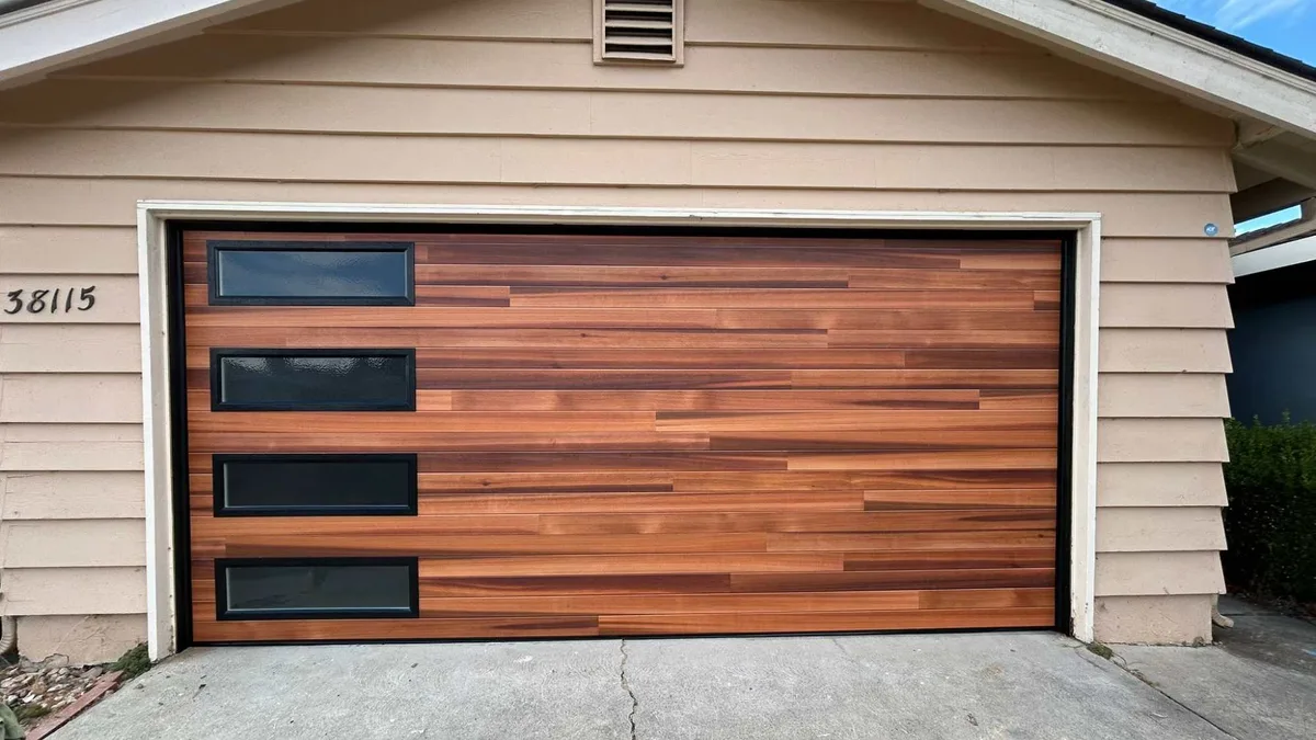 Wood-grain sectional garage door with black-framed rectangular windows